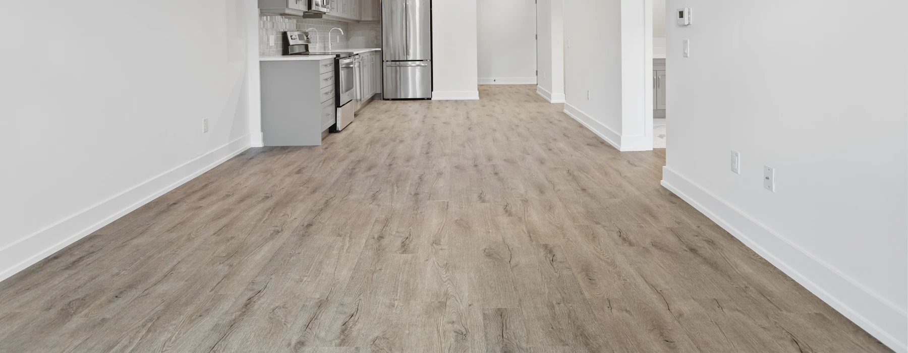 Pièce vide rénovée, parquet clair et murs blancs