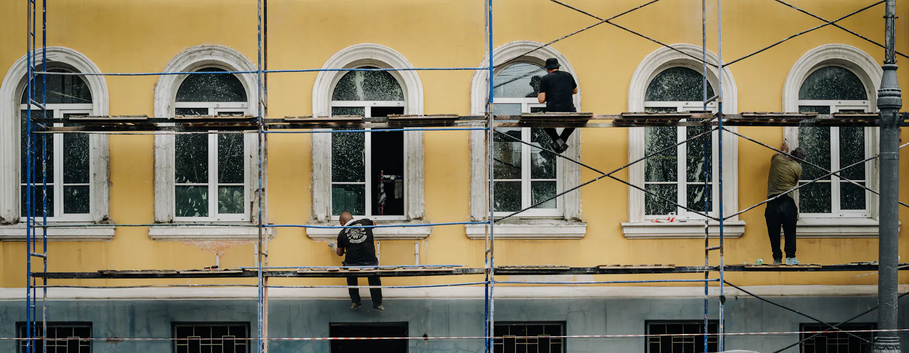 Ouvriers sur un échafaudage devant une façade jaune