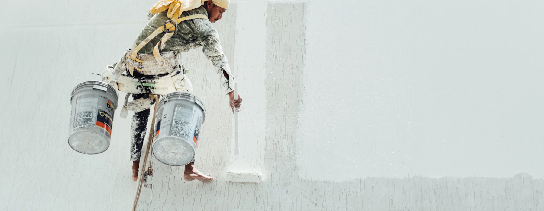 Peintre au travail sur un grand mur blanc